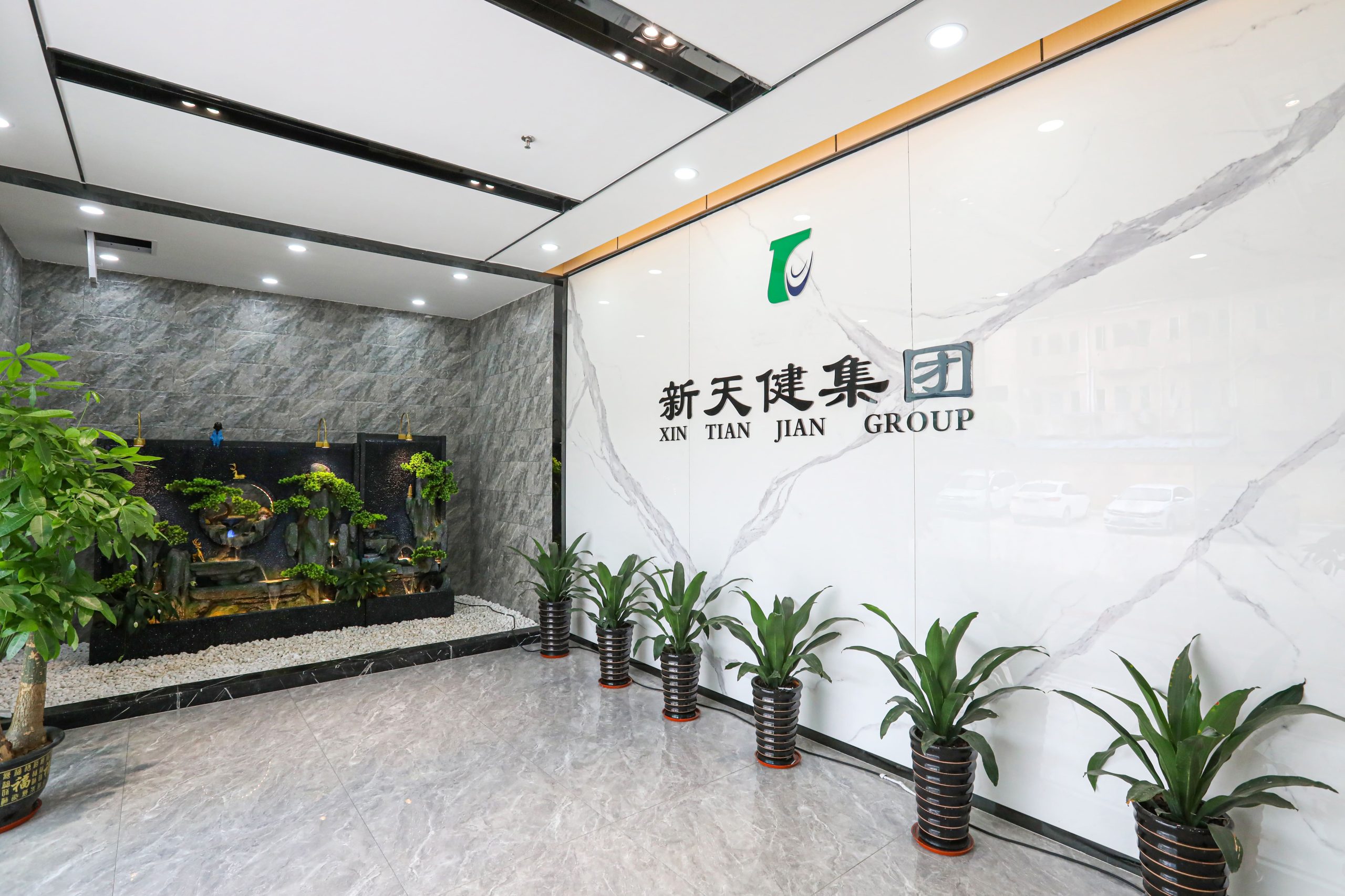 Entrance lobby of XTJ CNC with modern decor, marble walls, and potted plants.